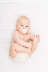 cute blond baby boy in diaper with pacifier
