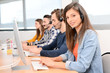 © W PRODUCTION - portrait of beautiful and cheerful young woman telephone operator with headset working on desktop computer in row in customer service call support helpline business center