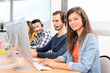 © W PRODUCTION - portrait of beautiful and cheerful young woman telephone operator with headset working on desktop computer in row in customer service call support helpline business center