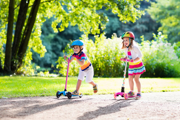 Kids riding scooter in summer park.