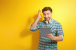 © Africa Studio - Handsome young man posing with tablet on color background