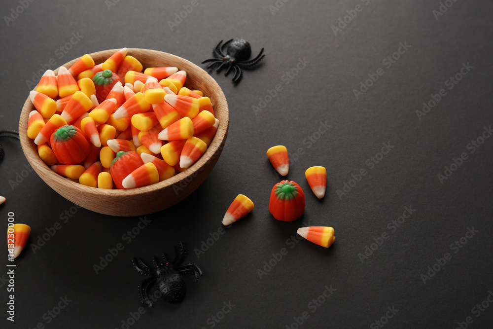 Bowl with tasty Halloween candies on dark background