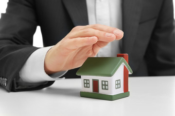 Sticker - Insurance concept. Man covering with hand toy house on table