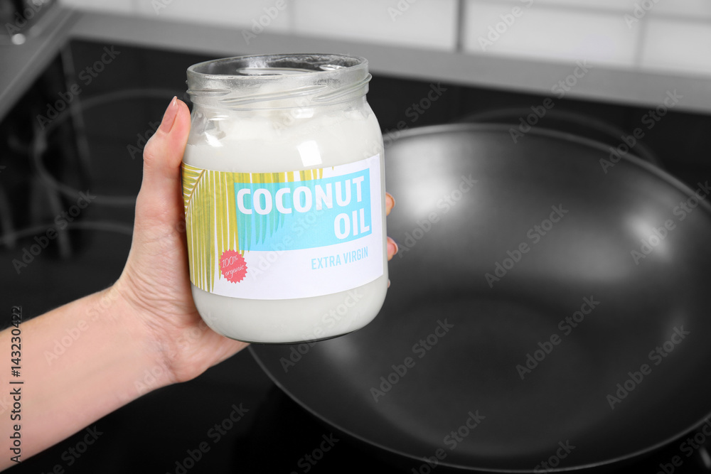 Female hand holding jar with coconut oil