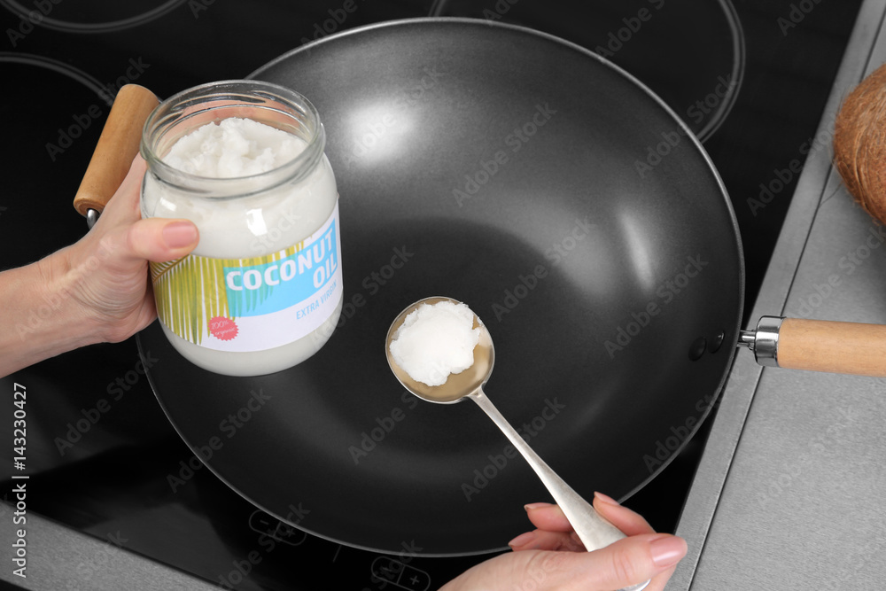 Woman putting coconut oil into frying pan