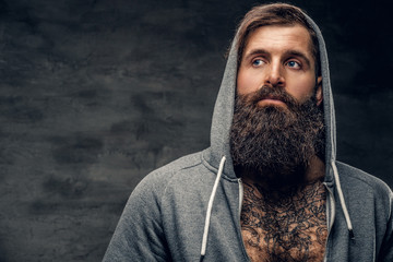 Wall Mural - Bearded male with tattoo on a chest, dressed in a grey hoodie.