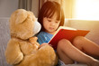 Leinwandbild Motiv Asian Chinese little girl reading book with teddy bear
