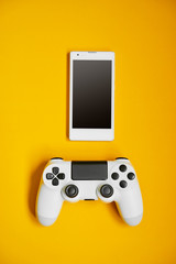 Wall Mural - Computer game competition. Gaming concept. White cellphone and joystick on yellow background.