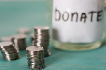Canvas Print - close-up view of stacked coins and glass jar for donate, donation concept