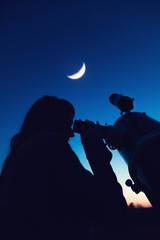 girl looking at the moon through a telescope. my astronomy work.