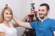 © Saksoni - Loving couple hanging decorations on Christmas tree