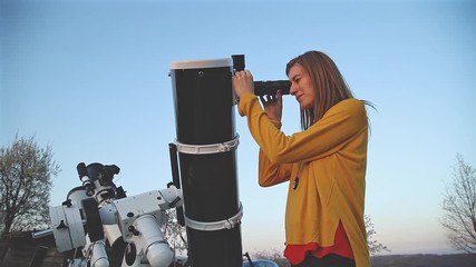 Wall Mural - girl looking at the sky through a telescope.