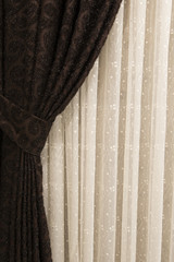 Beautifully draped long curtain on the window in the room. Close up of piled curtain. Luxury curtain, home decor. Brown panels. White lace drapery