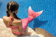 © Elvira - Mermaid girl with pink tail on rock at poolside put feet in water