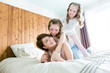 © Louis-Photo - Mother and two children in the bedroom on the bed