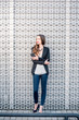 © rh2010 - Young elegant business woman in the suit standing outdoors with phone near the modern metal wall