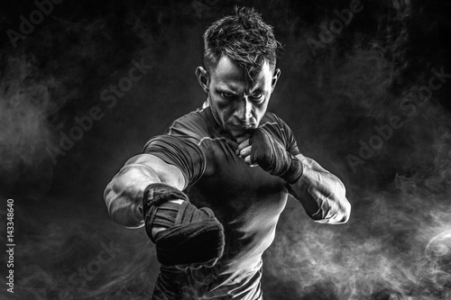 Studio portrait of fighting muscular man in smoke on black background Fototapete