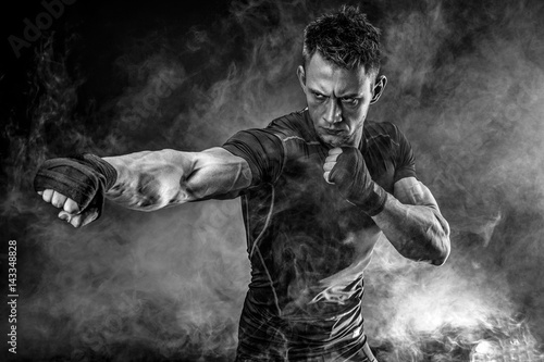 Foto Studio portrait of fighting muscular man in smoke on black background