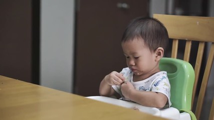 Wall Mural - 1 year and 3 months Asian baby eating chicken with bone by himself