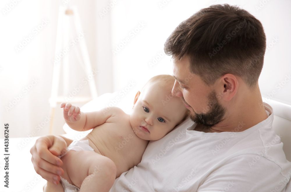 Father lying with cute baby daughter on bed at home
