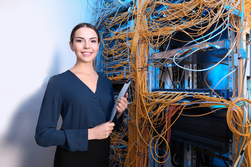 Beautiful young engineer with clipboard in server room