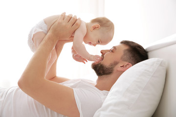 Poster - Father lying with cute baby daughter on bed at home