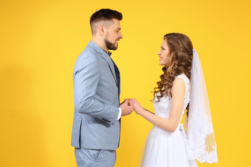 Canvas Print - Happy wedding couple holding hands on color background