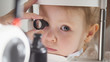 Child's ophthalmology - doctor optometrist checks eyesight for little girl