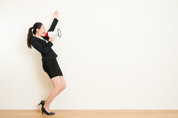 business woman talking in megaphone with white wall