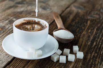 cup of coffee with milk and sugar spoon on the table