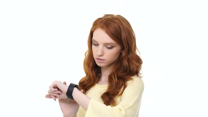 Poster - Smiling young woman with long curly red hair enjoys using smartwatch isolated over white