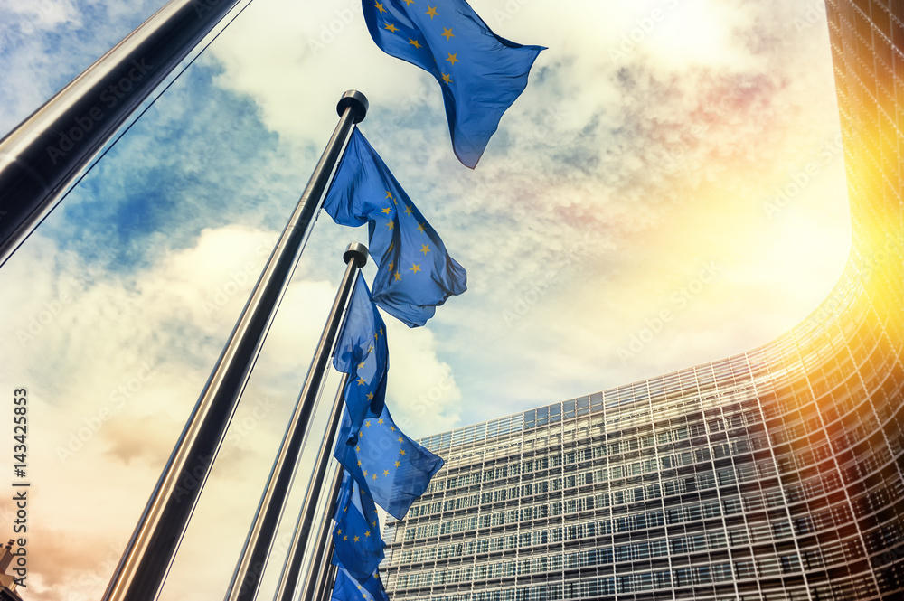 European Union flag waving in front of the European Commission building in Brussels.