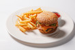 Fast food hamburger and french fries on a white plate