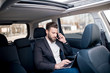 © rh2010 - Handsome businessman talking with phone sitting with laptop on the backseat of the car