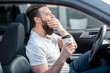 © rh2010 - Tired man yawning on the front seat of the car holding coffee to go