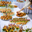 Beautifully decorated catering banquet table with burgers, profiteroles, salads and cold snacks. Variety of tasty delicious snacks on the table