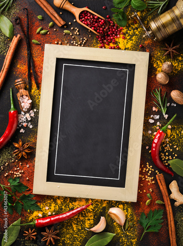 Photo Various spices and herbs surround blank blackboard