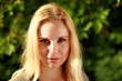 © StarlingRu - Looking at us blonde in the sunny forest, close-up portrait.