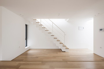 white empty living room with stair, wood floor, window, pendant lighting.