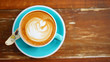 Flat lay of latte art on the blurred wooden table with copy space.