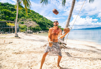 Wall Mural - funny young man juggling coconuts on the beach