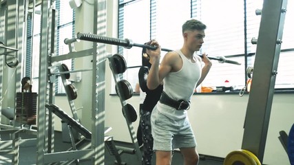 Poster - Fit young man in gym working out, lifting barbell