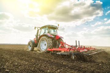 Farmer in tractor preparing land with seedbed cultivator as part of pre seeding activities in early spring season of agricultural works at farmlands.