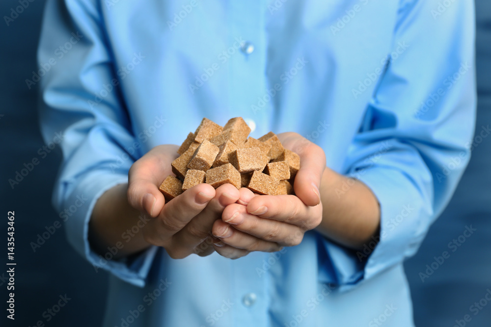 Woman holding brown refined sugar in hands, closeup