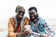 © santypan - Two black race friends having fun with mobile.