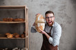 Screaming young man baker standing at bakery holding bread