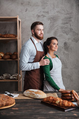 Sticker - Smiling loving couple bakers standing near bread.