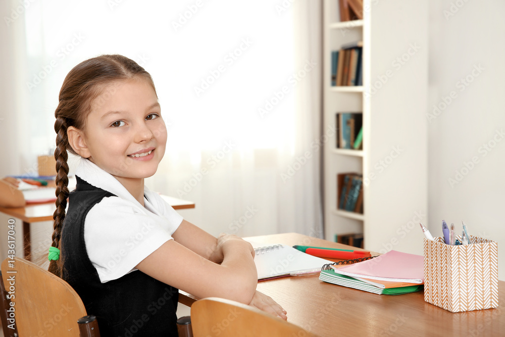 Beautiful elementary schoolgirl studying in classroom