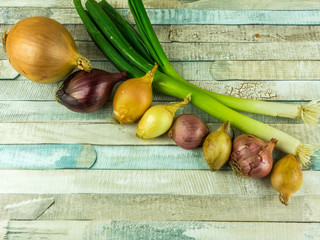 Various types of onions on a rustic wooden table