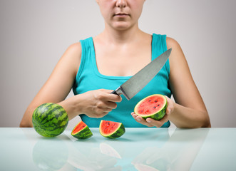 Canvas Print - Girl using big knife for cutting ripe red small watermelons